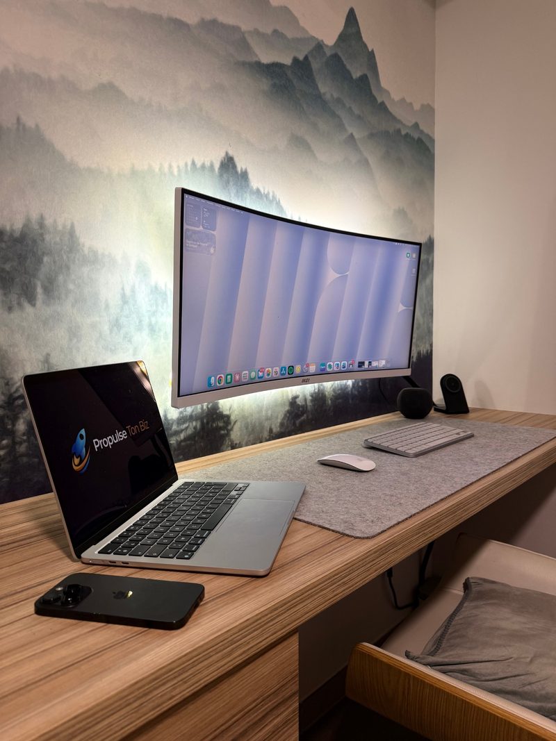 Mon bureau : MacBook avec le logo Propulse Ton Biz, écran incurvé et fond de montagnes